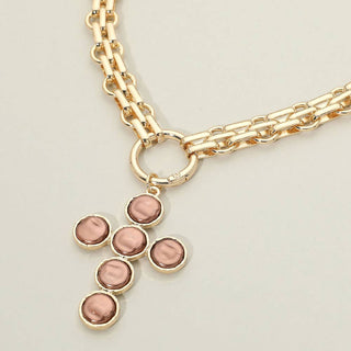 A gold-tone chain necklace featuring a cross-shaped pendant.
