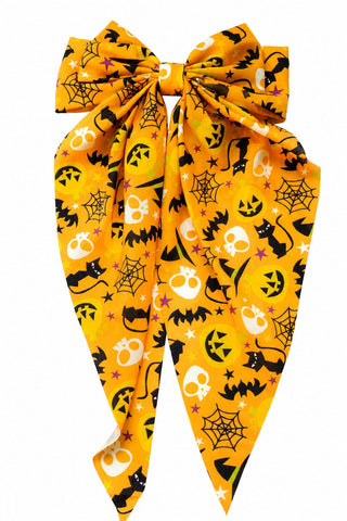 A orange bow accessory with a Halloween print featuring black bats, white skulls, black cats, spiderwebs, and jack-o'-lanterns.