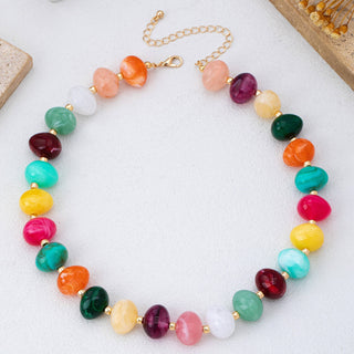 A multicolor beaded necklace with polished stone-like round beads in pink, orange, green, teal, yellow, red, and white, separated by small gold spacer beads and connected by a gold chain clasp.