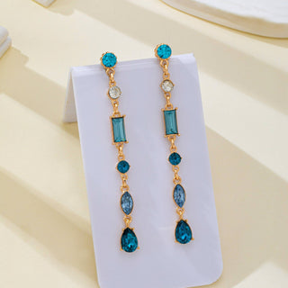 A pair of gold-tone drop earrings with multiple blue and teal gemstones.