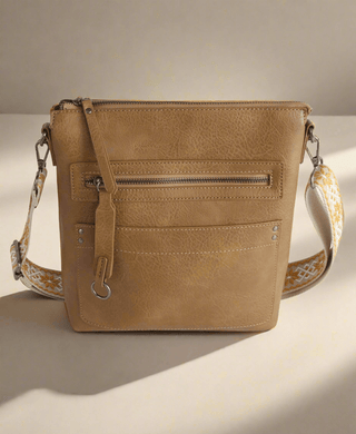 Brown leather crossbody bag with a patterned guitar strap 