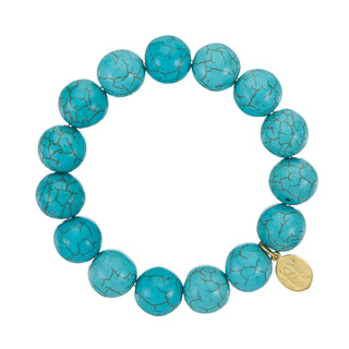 A stretch bracelet composed of large round turquoise beads with brown veining, featuring a small gold-tone branded charm,.
