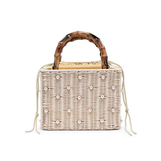 A structured woven straw top-handle bag with pearl stud accents and bamboo-style handles