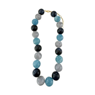 A beaded necklace featuring alternating round beads of light blue, dark navy, and translucent light gray, completed with a small gold clasp.