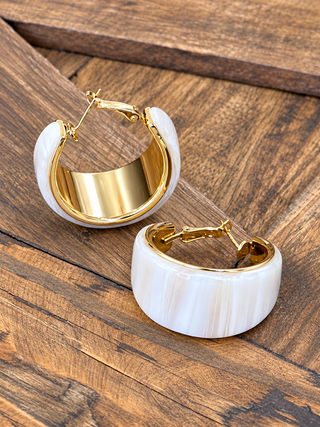 A pair of gold hoop earrings with thick, rounded ivory resin outer shells.