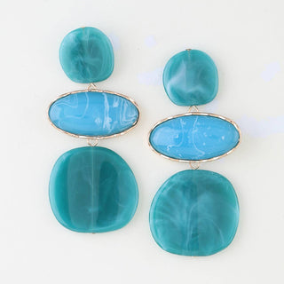 A pair of statement drop earrings featuring marbled turquoise blue and teal resin stones in an oval and rounded square shape, set in silver-tone metal.
