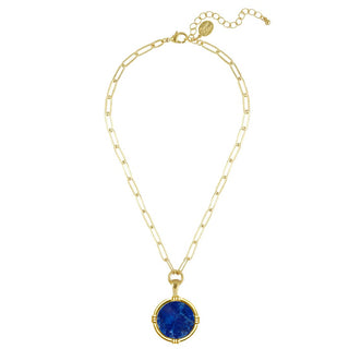 A gold chain necklace featuring a large, round, deep blue lapis lazuli-style stone pendant in a gold bezel setting by Susan Shaw.