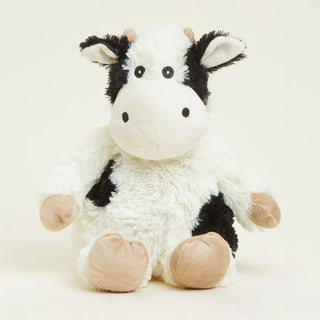 A plush warmie cow with a fluffy white and black fur pattern, featuring beige hooves and ears.