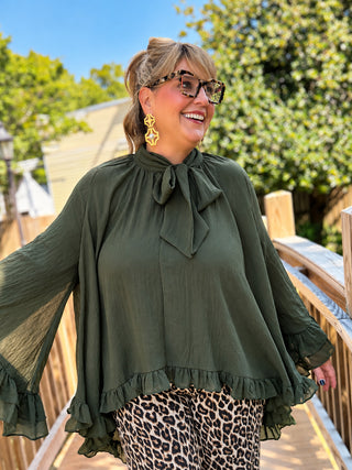 flowy poncho-style blouse, finished with a self-tie neckline, dramatic wide sleeves, and layered ruffle trim.