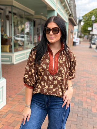  Half-Zip is a floral print top with puff sleeves and a half-zip neckline and pop collar look