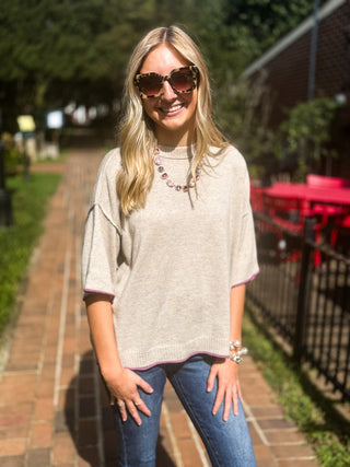 oversized tan sweater with purple trim on sleeves and hem with short sleeves