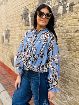 Blouse in dusty blue, made from 100% cotton with brown and white floral design and ruffle cuffs