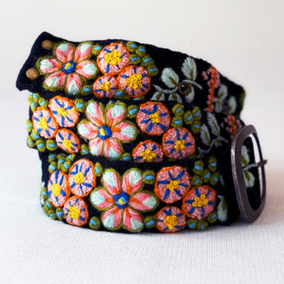 A black felt belt featuring vibrant, multicolored floral embroidery with pink, orange, blue, green, and yellow threads, complete with a dark metal buckle.