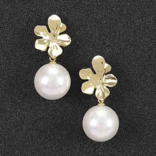 A pair of gold flower-shaped drop earrings with large white pearl drops.