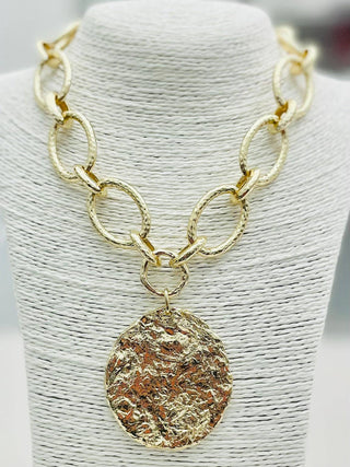 Gold chain necklace with a hammered round pendant.