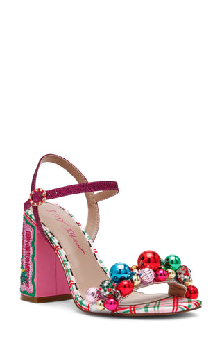 A festive Christmas-themed heeled sandal by Betsey Johnson, featuring a pink glitter ankle strap, a pink block heel with embroidered green and red plaid detailing, and a strap adorned with colorful red, green, blue, and pink decorative beads.