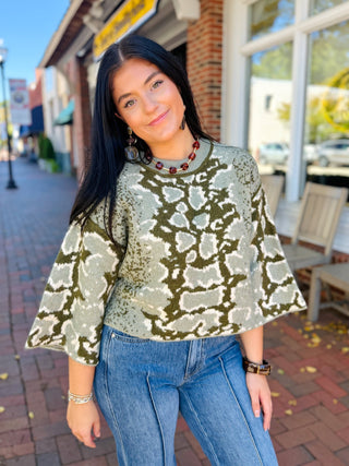 cropped knit sweater in olive, featuring a two-tone abstract floral jacquard pattern, a relaxed boat neckline, and wide flared sleeves