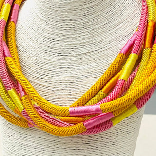 Necklace with pink and yellow braided cords.
