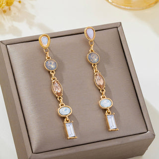 A pair of gold linear drop earrings with light blue, pink, and clear gemstones.