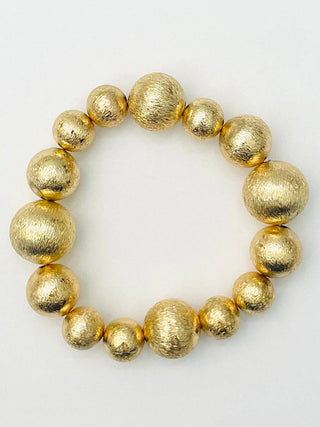 A gold beaded bracelet with textured, metallic spherical beads of varying sizes.