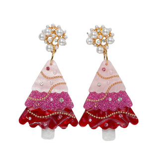 A pair of dangling earrings shaped like tiered Christmas trees, featuring a light pink top section, a glittery magenta middle section, and a deep red ruffled bottom section, accented with gold-tone chains, clear rhinestones, and white faux pearl clusters at the top.