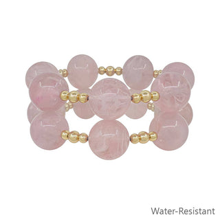 Pink beaded bracelet set with gold accents.