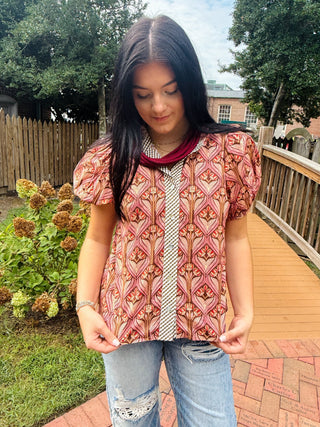 cinnamon color blouse with short puff sleeves, a ruffled neckline, and a button front closure
