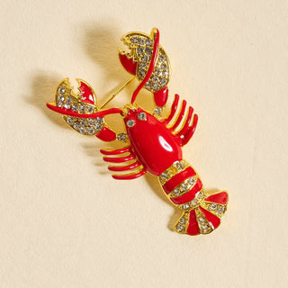Lobster-shaped brooch with red body and gold accents.