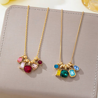 Two gold-tone charm necklaces. Each necklace has a delicate chain with a cluster of small gold beads and multiple colorful gemstone charms, including pink, red, light pink, green, blue, and yellow stones.