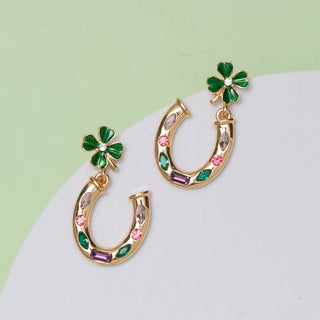 Gold horseshoe earrings with green clover leaves and colorful stones.