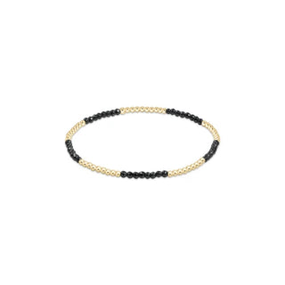 A delicate stretch bracelet featuring alternating small faceted black hematite beads and polished 14K gold filled beads by Enewton.