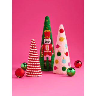 Three festive felt Christmas tree ornaments in red, green, and pink, styled with colorful holiday baubles on a vibrant pink background.