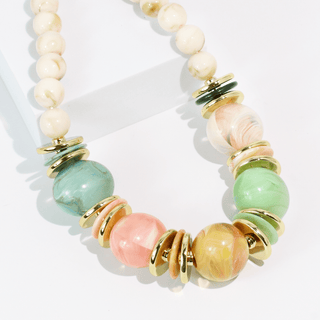 A beaded necklace with large marbled beads in pastel pink, mint green, and aqua blue, accented by gold-toned metal spacers and cream-colored round beads.