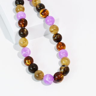 A beaded necklace made of polished round gemstone beads in amber brown, dark brown, light tan, and lavender purple.