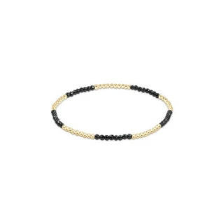 A delicate stretch bracelet featuring alternating small faceted black hematite beads and polished 14K gold filled beads by Enewton.