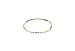 A slim stretch beaded bracelet alternating small 14K gold filled and faceted dark silver-toned hematite beads by Enewton.