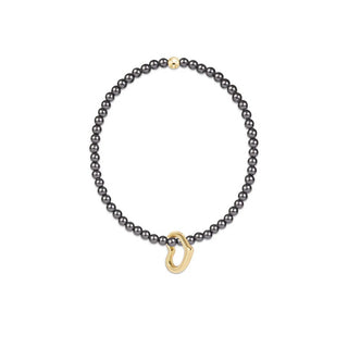 A bracelet featuring a strand of small, dark gray pearls and a polished gold-tone open heart-shaped pendant by Enewton.