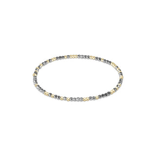 A delicate 2mm stretch bracelet featuring alternating faceted silver metallic hematite beads and smooth 14K gold filled beads by Enewton.