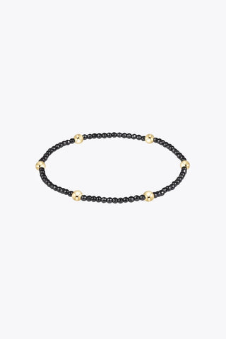 A stretch beaded bracelet composed of small faceted black hematite beads with evenly spaced 14K gold filled accents beads by Enewton.