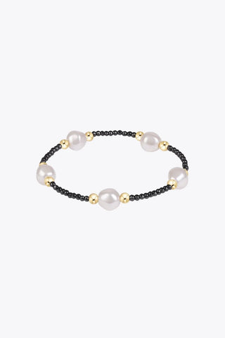 A stretch beaded bracelet featuring large white pearl beads and 14K gold filled accent beads set against a strand of small faceted black hematite micro-beads by Enewton.