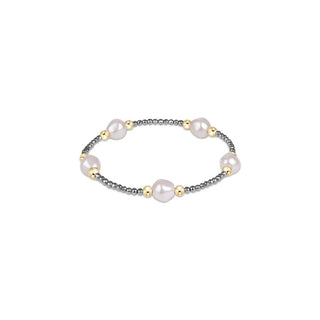 A stretch beaded bracelet featuring five baroque-style white pearls and round 14K gold filled beads spaced along a strand of small faceted silver hematite beads by Enewton.