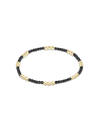 A slim stretch bracelet featuring alternating clusters of polished 14K gold-filled beads and small faceted black hematite beads by Enewton.