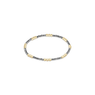 A stretch beaded bracelet featuring alternating clusters of polished 14K gold-filled beads and small faceted dark silver hematite beads by Enewton.