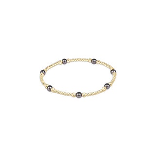 A stretch beaded bracelet with small 14K gold-filled beads and evenly spaced dark grey pearl crystal accents by enewton.