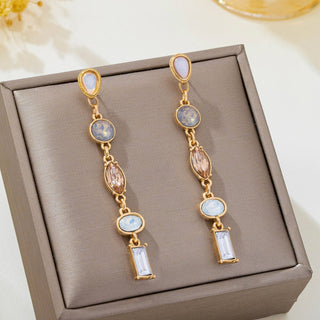 A pair of gold linear drop earrings with light blue, pink, and clear gemstones.