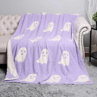 A reversible  purple fleece throw blanket with white ghost patterns.