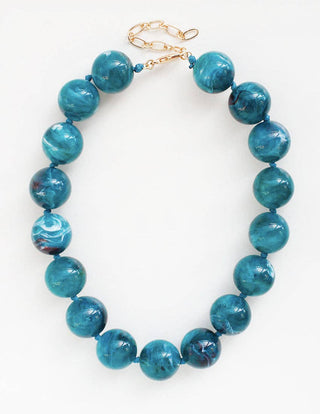 A beaded necklace made of glossy, marbled teal-blue beads with a gold-tone lobster clasp.