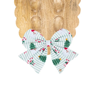 A large magnetic bow with light green vertical stripes and a Christmas print featuring green trees, red hats, and small red accents.