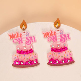Pink cake-shaped earrings with 'Make a Wish' text 