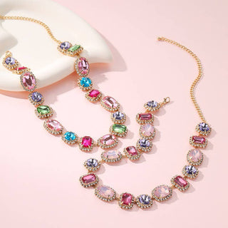 Two gold-tone multi-strand statement necklaces with colorful faceted gemstones in pink, purple, blue, and green.